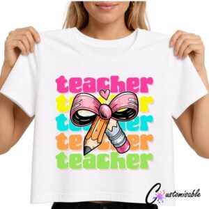 White T-shirt with a bright “Teacher” DTF transfer design featuring repeated colourful teacher text, a large pink bow, pencil, and eraser illustration.