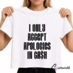 White T-shirt with bold black text reading “I Only Accept Apologies In Cash” in a stacked DTF transfer design.
