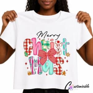 White T-shirt with colourful “Merry Christmas” DTF transfer design featuring patterned festive lettering, a red bow, stars, candy cane details, and holiday icons.