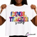 White T-shirt with “Cool Teacher Vibes” DTF transfer design featuring colourful tie-dye-style block lettering and black script text.