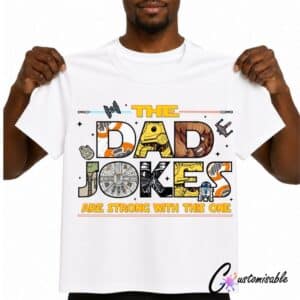 White T-shirt with “The Dad Jokes Are Strong With This One” DTF transfer design featuring colourful sci-fi-inspired lettering, space icons, and bold dad joke typography.