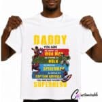 White T-shirt with a superhero-inspired “Daddy You Are Our Favourite Superhero” DTF transfer design featuring colourful comic-style graphics and bold text.