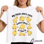 White T-shirt with “My Ducks Don’t Even Know What A Row Is” DTF transfer design featuring cute yellow duck illustrations and small daisy accents.