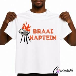 White T-shirt with “Braai Kaptein” DTF transfer design featuring red-orange text, a black braai grill illustration, and flame detail.