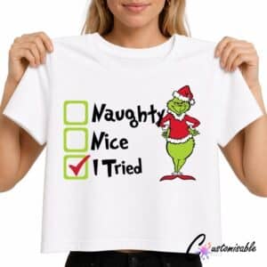 White T-shirt with Christmas DTF transfer design reading “Naughty Nice I Tried” with checkbox graphics and a green festive character wearing a Santa outfit.