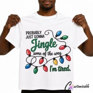 White T-shirt with Christmas DTF transfer design reading “Probably Just Gonna Jingle Some Of The Way I’m Tired” with colourful string lights.